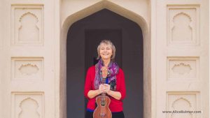 woman wearing red sweater standing in entrance holding ukulele
