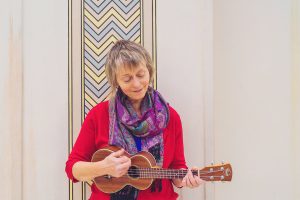 Woman in red cardigan laying ukulele